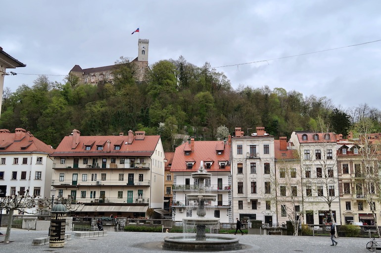 Panorama do centro histórico de Liubliana, com o castelo ao fundo, atrás dos prédios seculares.