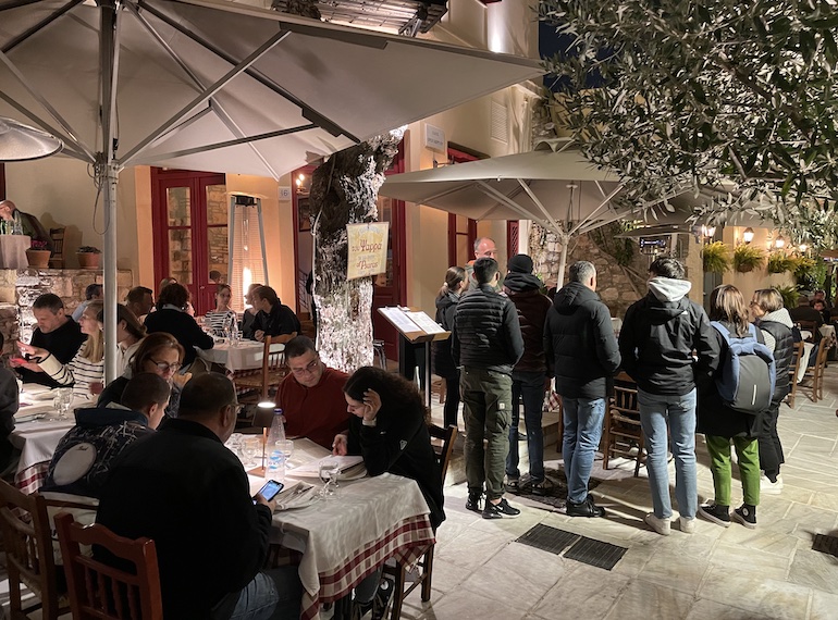 Mesas nas calçadas no bairro de Plaka, local com a noite mais animada de Atenas e uma ótima região para se hospedar, repleta de hotéis e pousadas.