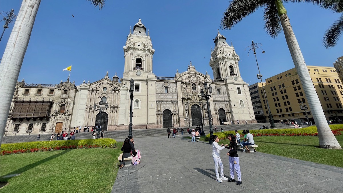 Dia ensolarado na Praça Maior de Lima, com turistas fotografando a catedral, nesta que é a melhor área para se hospedar no centro da capital peruana.